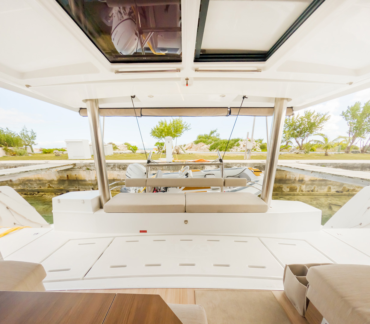 A white boat is anchored on calm water, reflecting the clear blue sky above.
