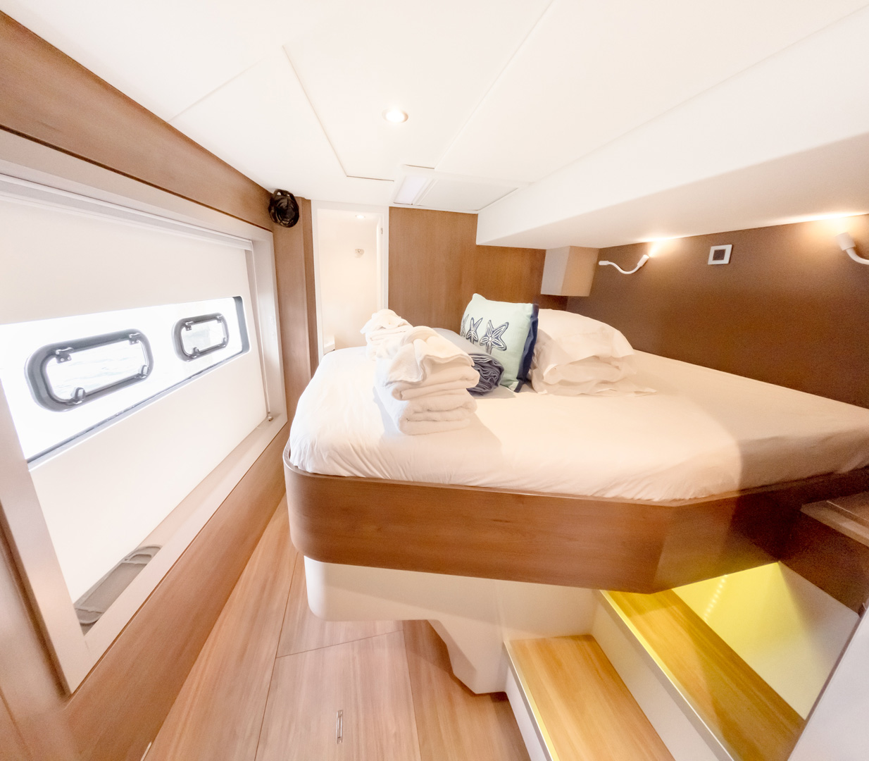 Interior of a boat featuring a cozy bed beside a window, allowing natural light to illuminate the space.
