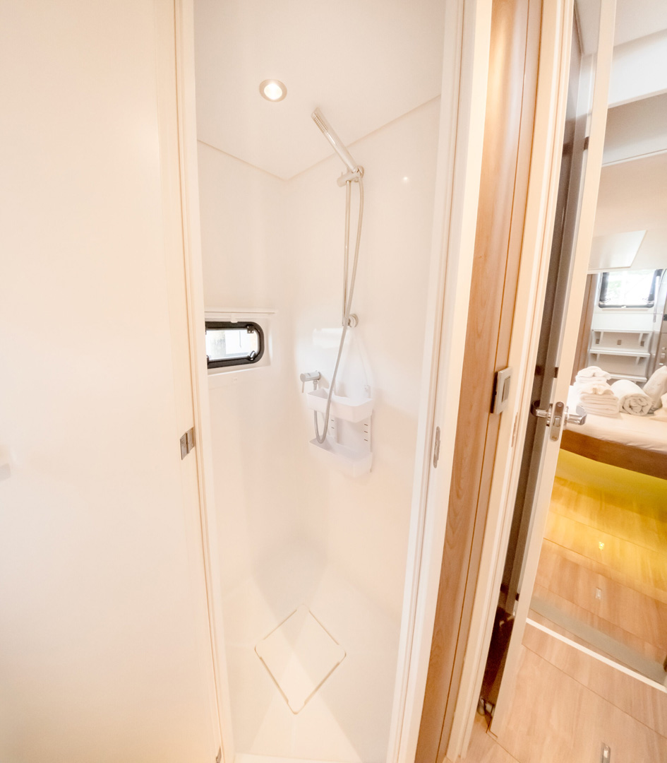 A bathroom featuring a shower and a toilet, with neutral-colored tiles and modern fixtures.