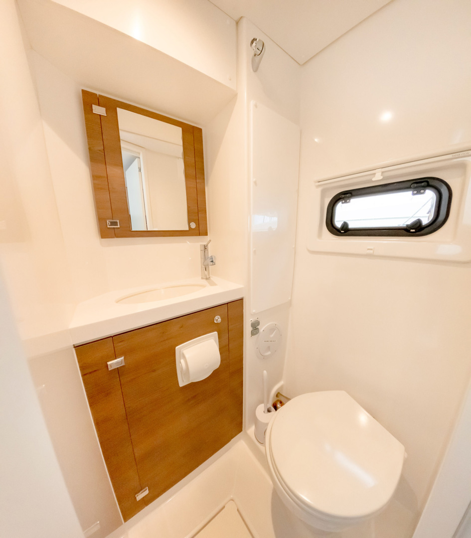 A bathroom featuring a toilet, sink, and mirror, with neutral-colored walls and tiled flooring.