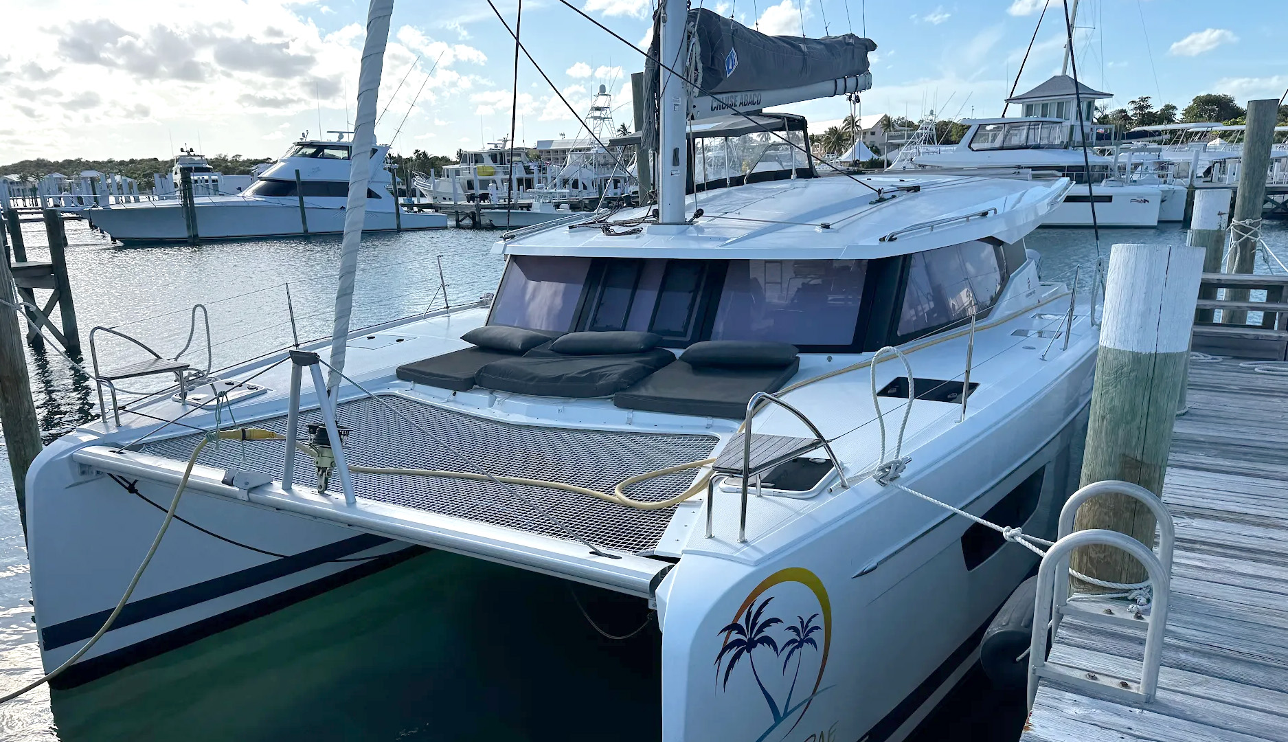 A boat rests on the beach beside another white boat, with sand and gentle waves in the background.