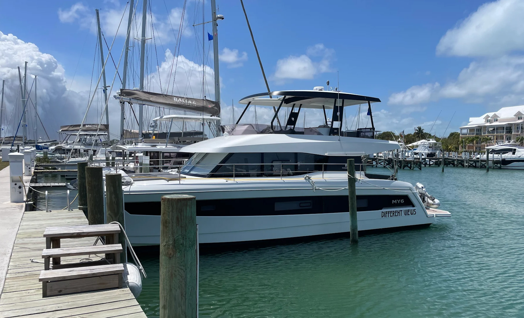 A boat rests on the beach beside another white boat, with sand and gentle waves in the background.