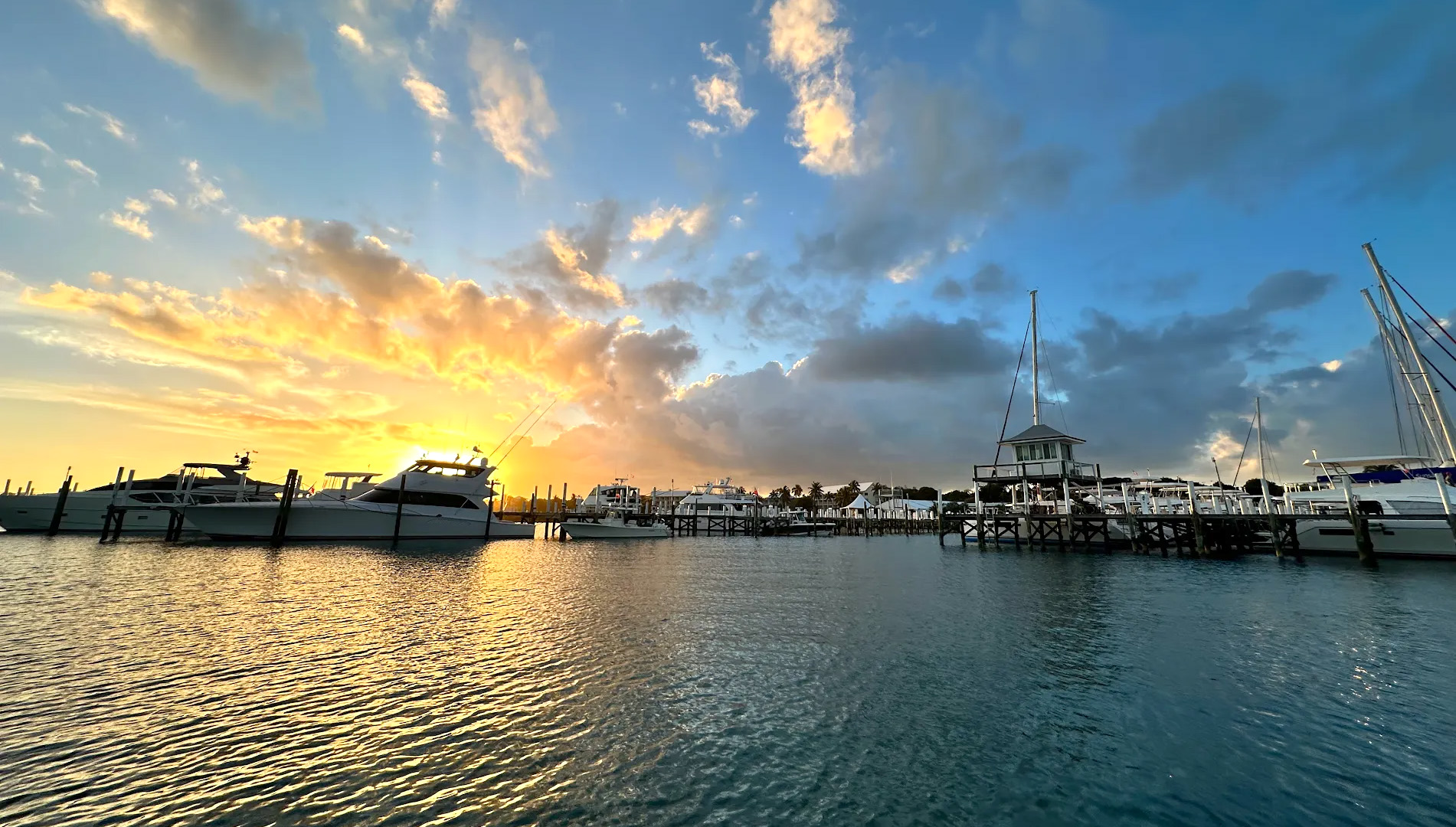 A boat rests on the beach beside another white boat, with sand and gentle waves in the background.