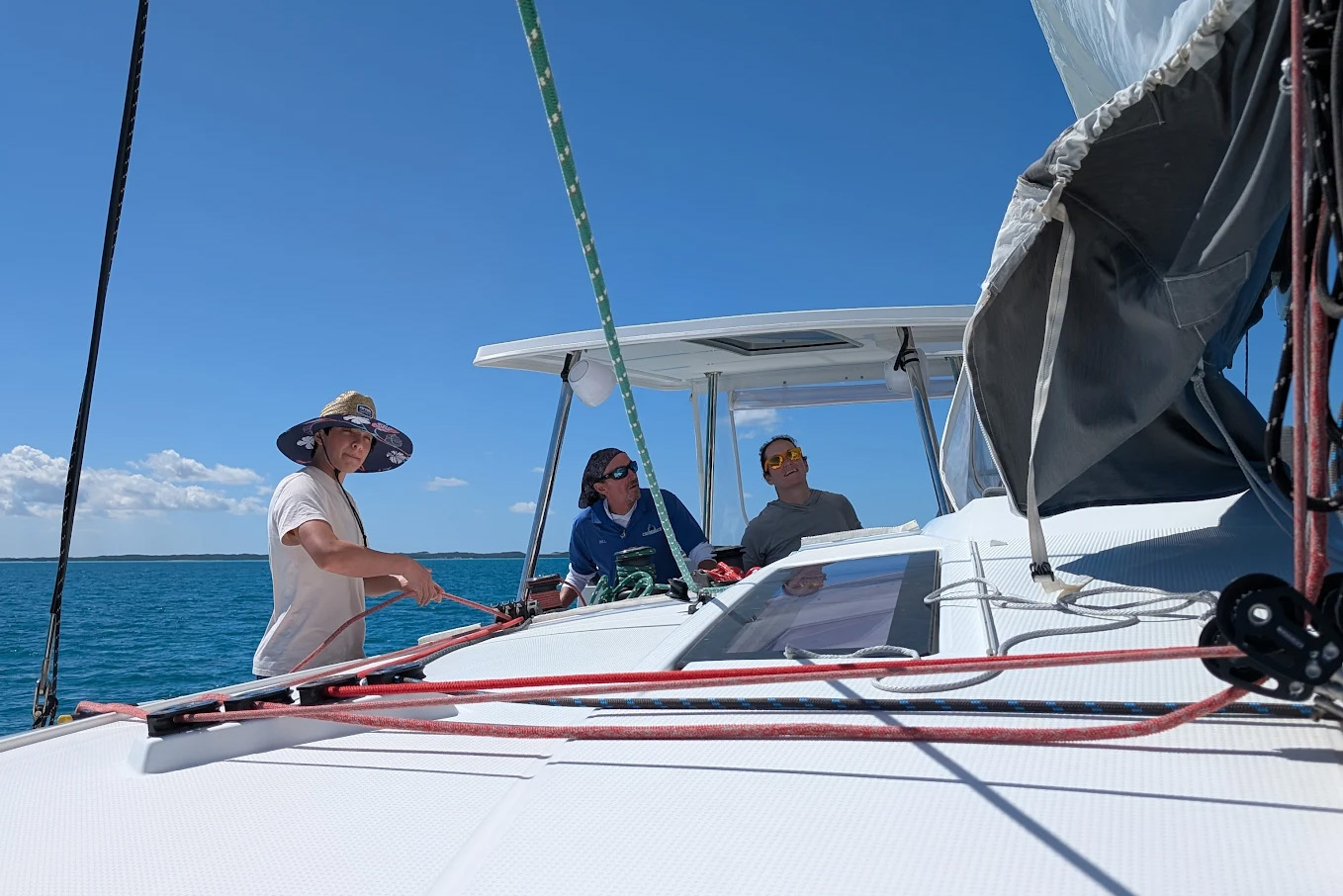 A boat rests on the beach beside another white boat, with sand and gentle waves in the background.