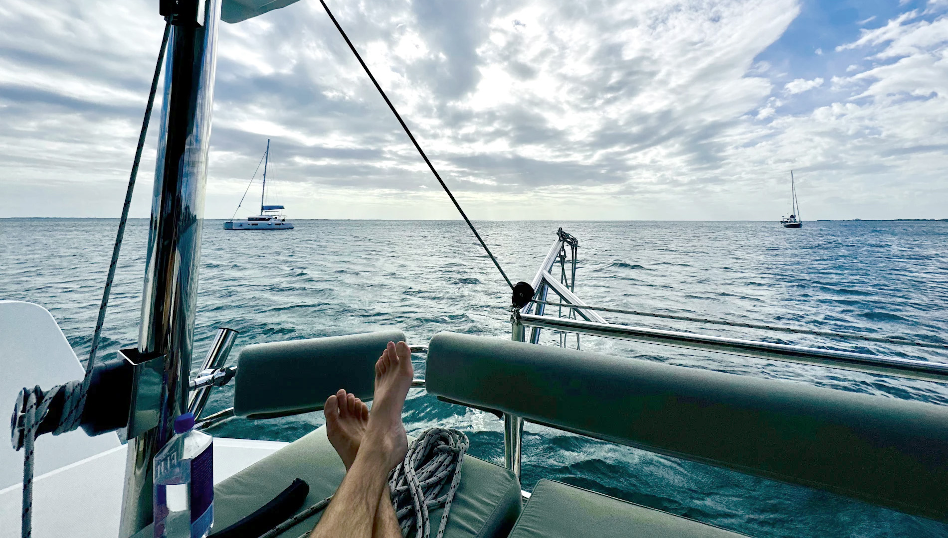 A boat rests on the beach beside another white boat, with sand and gentle waves in the background.