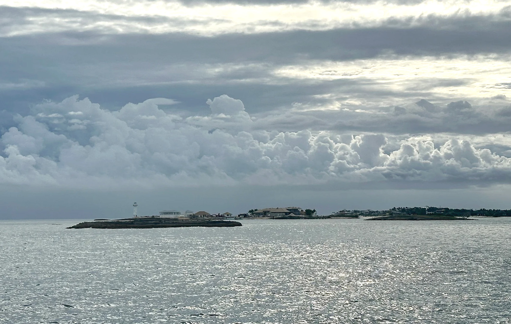 A boat rests on the beach beside another white boat, with sand and gentle waves in the background.