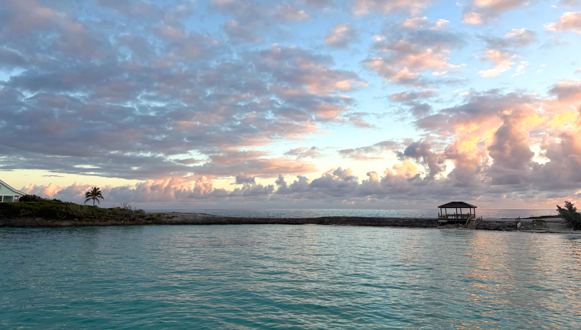 A boat rests on the beach beside another white boat, with sand and gentle waves in the background.